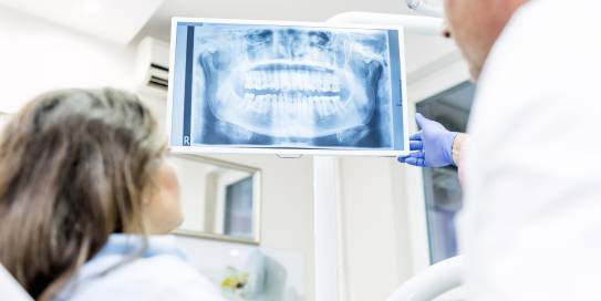 Zahnarzt zeigt Patientin Röntgenaufnahmen