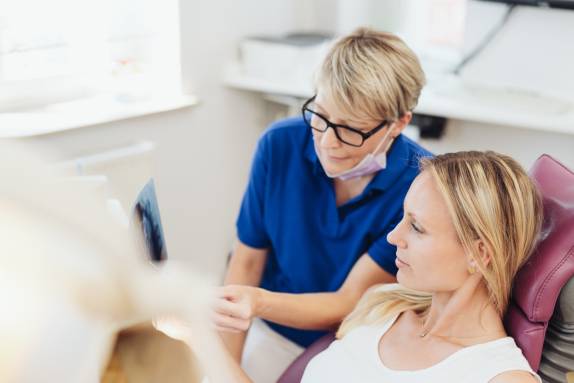 ZFA zeigt Patientin Röntgenaufnahmen